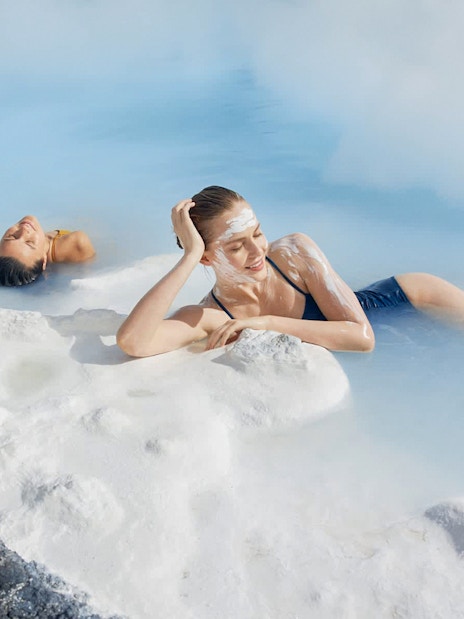 Female tourist relaxing in Blue Lagoon, Iceland, with silica mud on face.