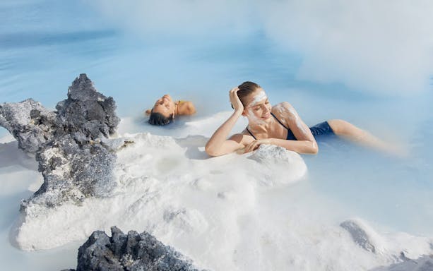 Female tourist relaxing in Blue Lagoon, Iceland, with silica mud on face.