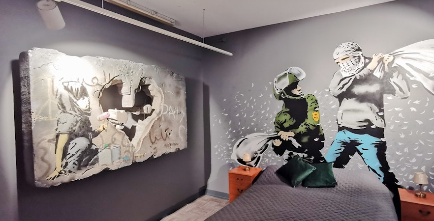 Banksy artwork featuring a heart-shaped hole and figures in a room setting.