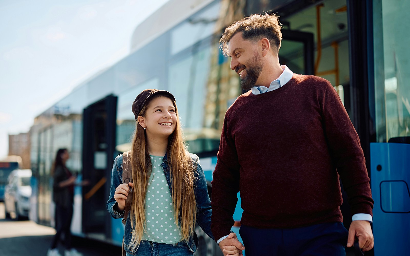 Kid and parent smiling while exiting a bus.