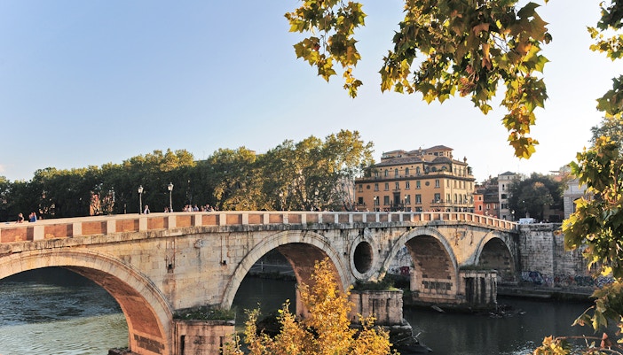 Ponte Sisto bridge over Tiber River in Rome with St. Peter's Basilica in the background.