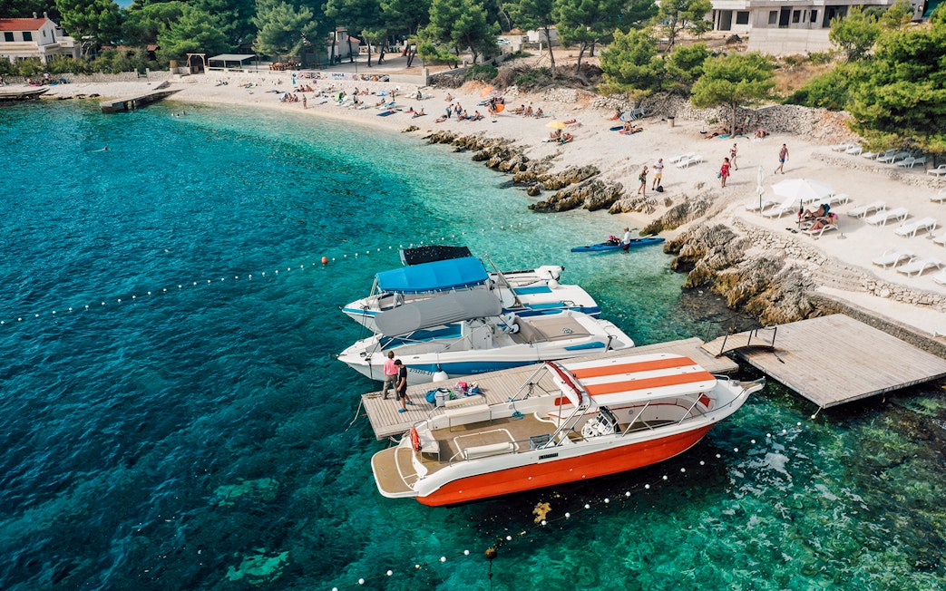 Speedboats docked at Blue Lagoon with beachgoers relaxing nearby.