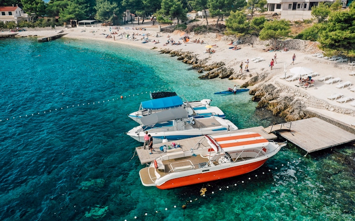 Speedboats docked at Blue Lagoon with beachgoers relaxing nearby.