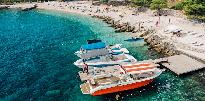 Speedboats docked at Blue Lagoon with beachgoers relaxing nearby.
