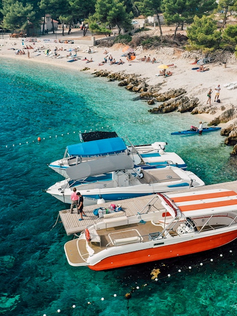 Speedboats docked at Blue Lagoon with beachgoers relaxing nearby.
