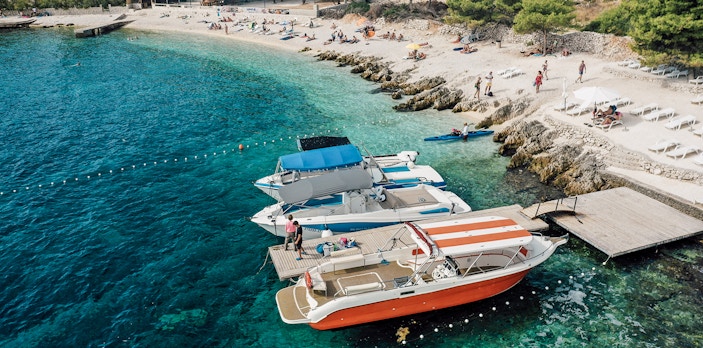 Speedboats docked at Blue Lagoon with beachgoers relaxing nearby.