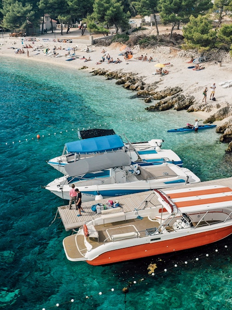 Speedboats docked at Blue Lagoon with beachgoers relaxing nearby.