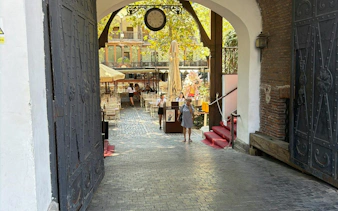 Courtyard entrance in Bucharest's Armenian Quarter with outdoor seating.