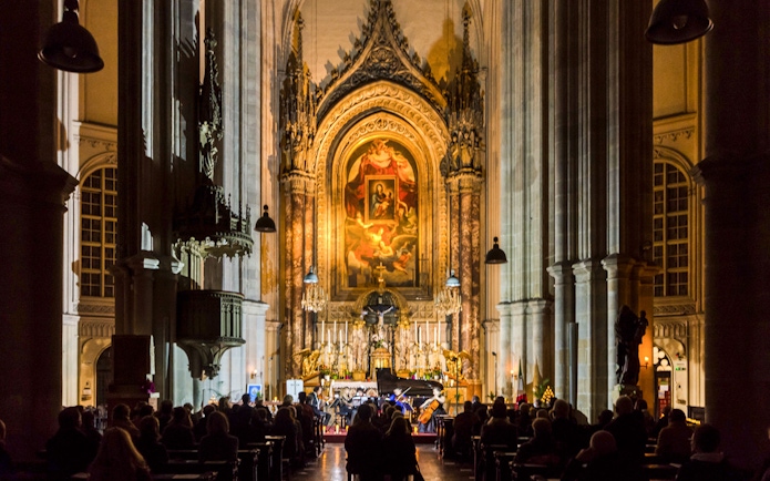 Classical concert at Minoritenkirche with audience seated in the illuminated church interior.