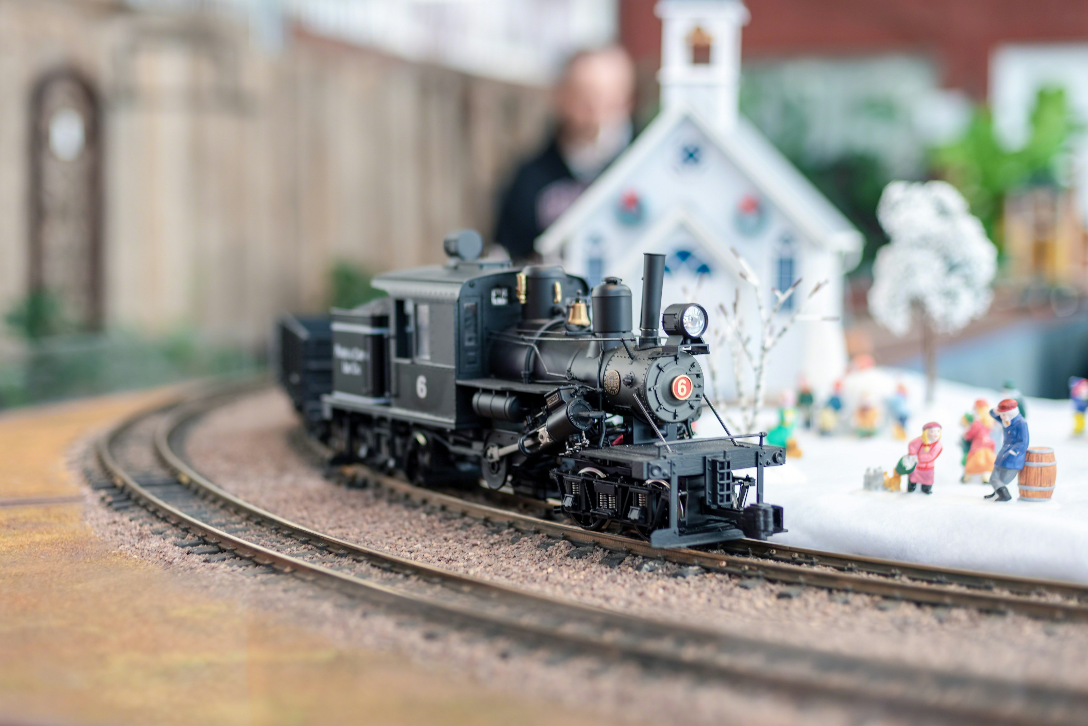 Miniature trains navigating through a detailed model cityscape at the Holiday Train Show, New York.
