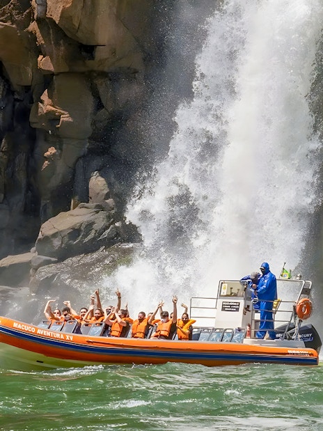 Tourists on a boat near Iguazú Falls, Brazilian side, with waterfall in background.