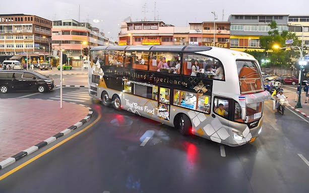 Double-decker bus on Thai street offering a food tour experience.