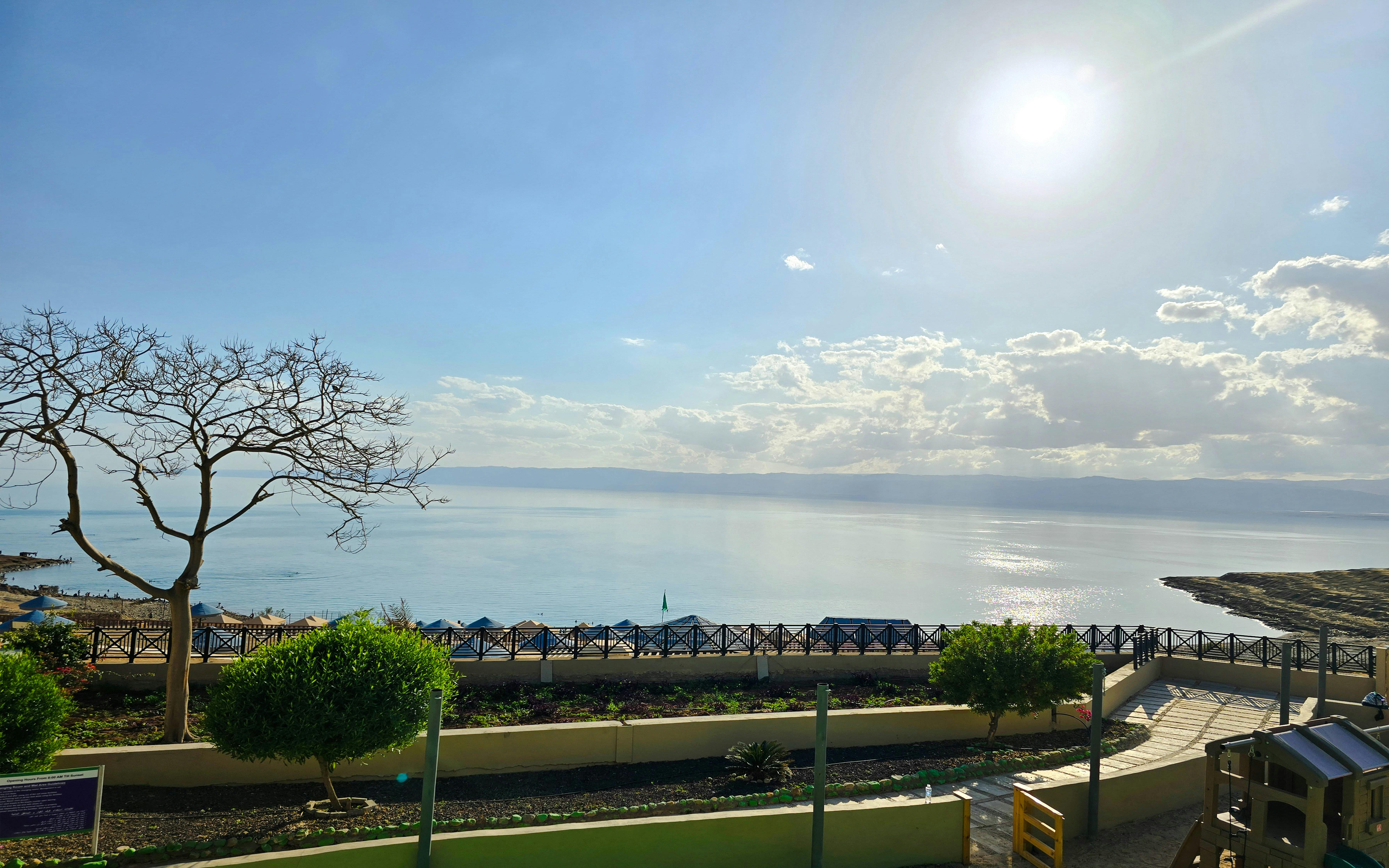Private 4-star resort view of the Dead Sea, Jordan, with sunlit water and landscaped gardens.