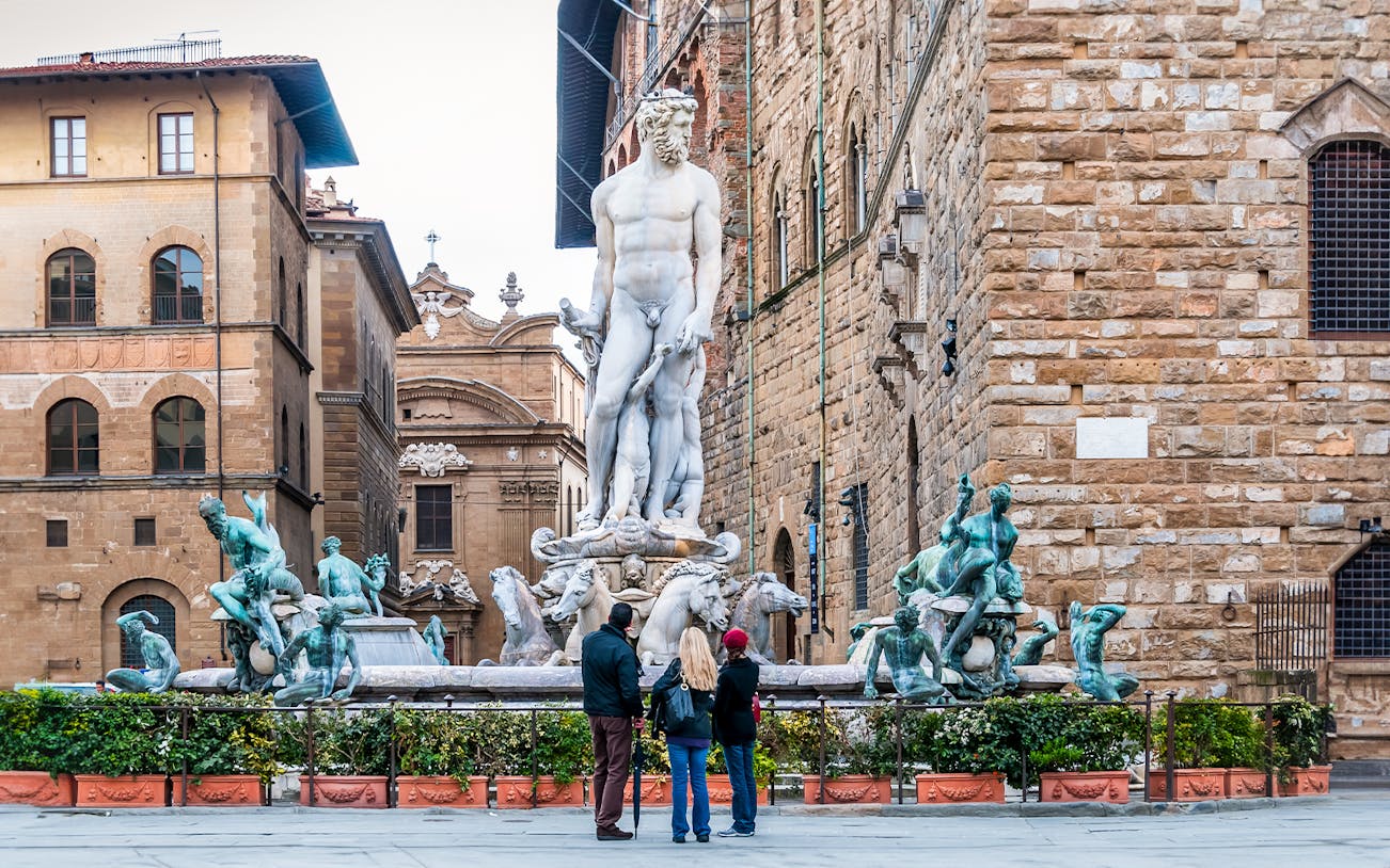 Visitors admiring Neptune statue in Piazza della Signoria, Florence.