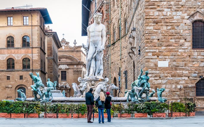Visitors admiring Neptune statue in Piazza della Signoria, Florence.