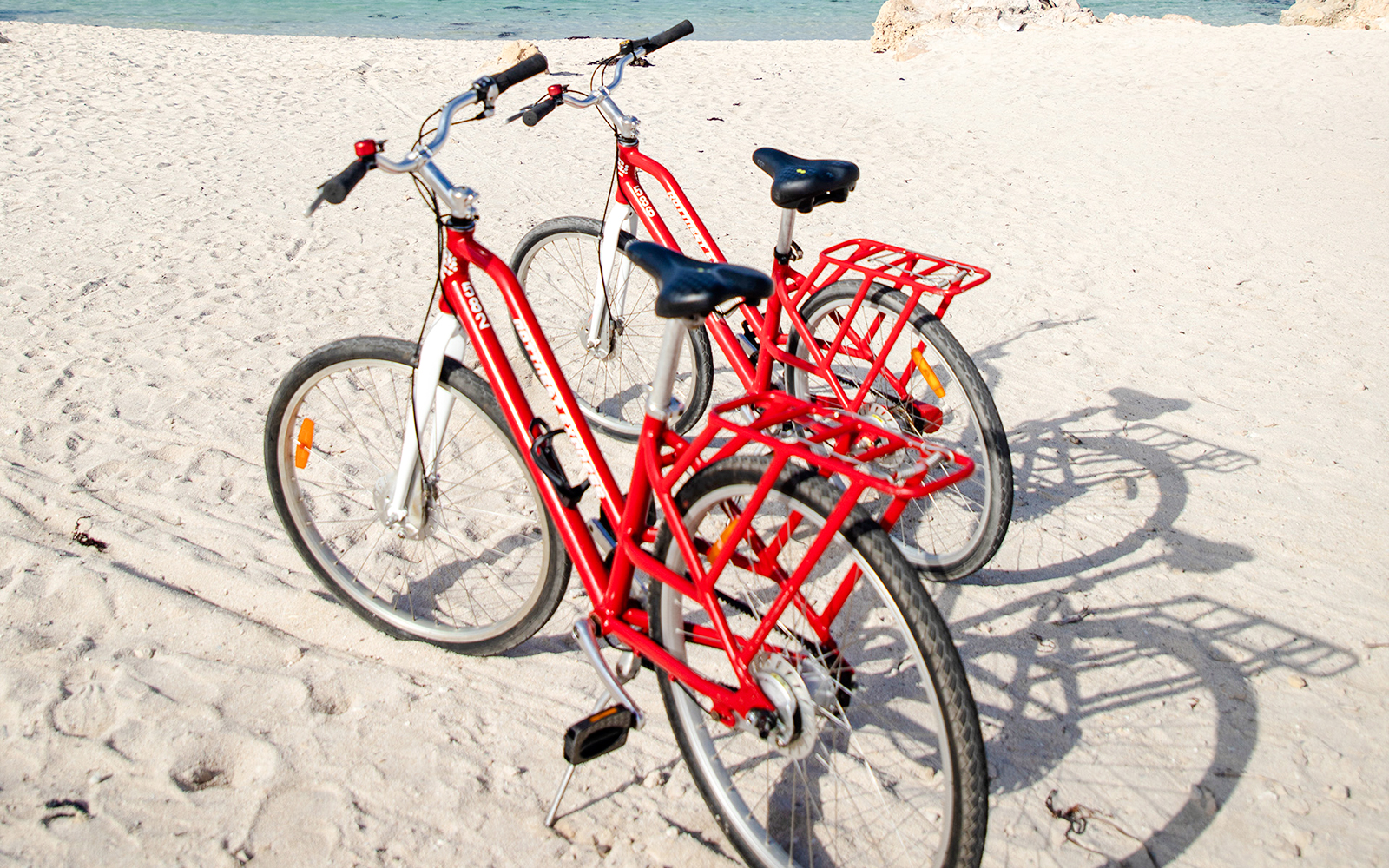 Red bicycles on sandy beach with ocean in background, Rottnest Island, Western Australia.