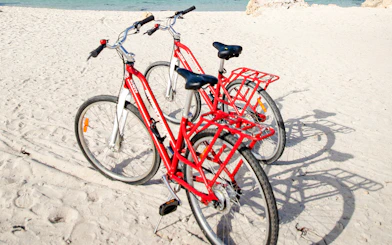 Red bicycles on sandy beach with ocean in background, Rottnest Island, Western Australia.