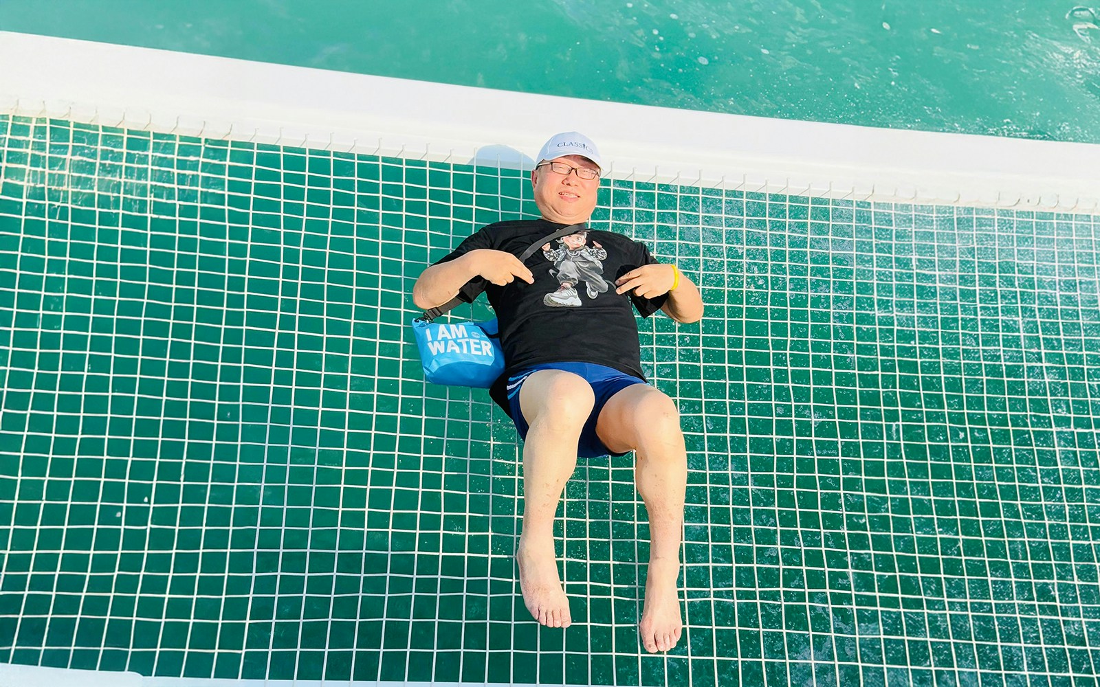Man relaxing on a jacuzzi net over turquoise waters during Langkawi Island hopping tour.