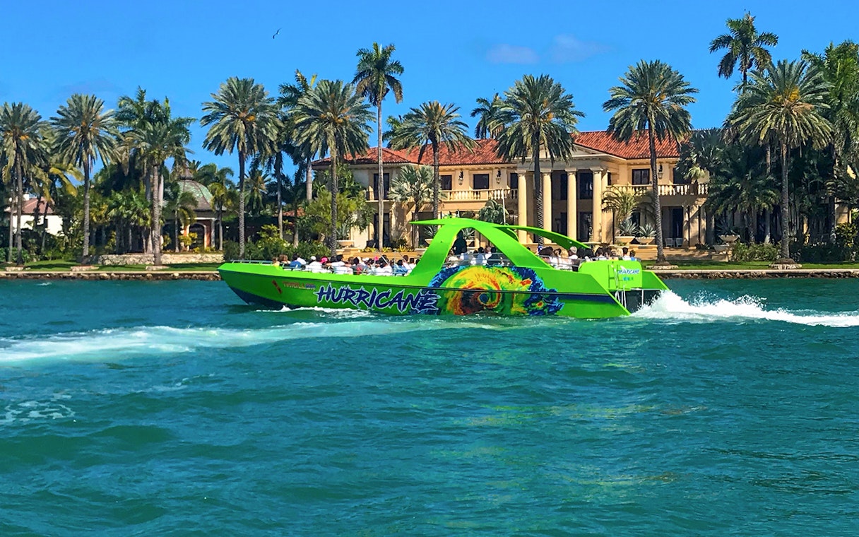 Speedboat cruising past waterfront mansion in Miami.