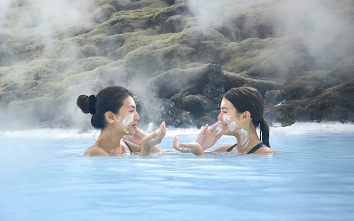 Female tourists applying face masks at Blue Lagoon, Iceland.