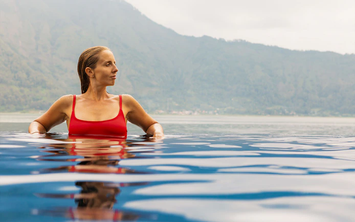 Person relaxing in Toya Devasya hot spring with mountain view in the background.