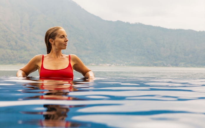 Person relaxing in Toya Devasya hot spring with mountain view in the background.