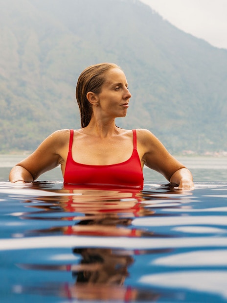 Person relaxing in Toya Devasya hot spring with mountain view in the background.
