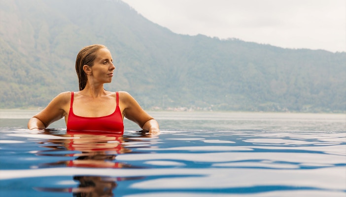 Person relaxing in Toya Devasya hot spring with mountain view in the background.