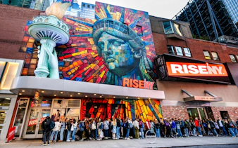 Exterior mural of Rise NY with Statue of Liberty mosaic and people in line, New York City.