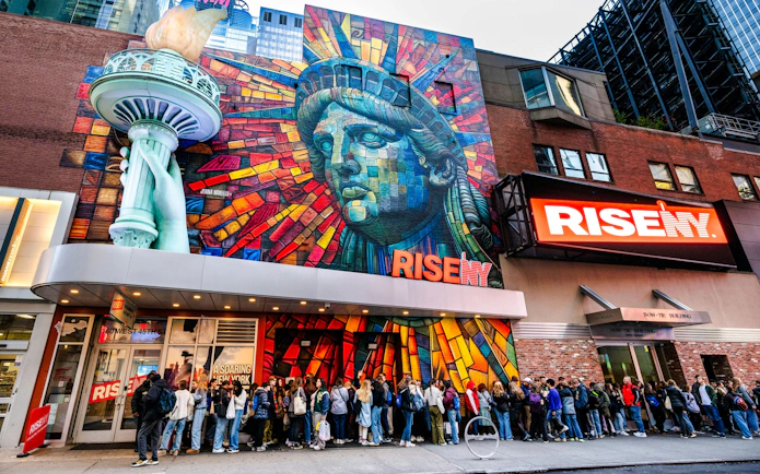 Exterior mural of Rise NY with Statue of Liberty mosaic and people in line, New York City.