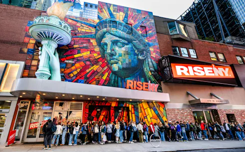 Exterior mural of Rise NY with Statue of Liberty mosaic and people in line, New York City.