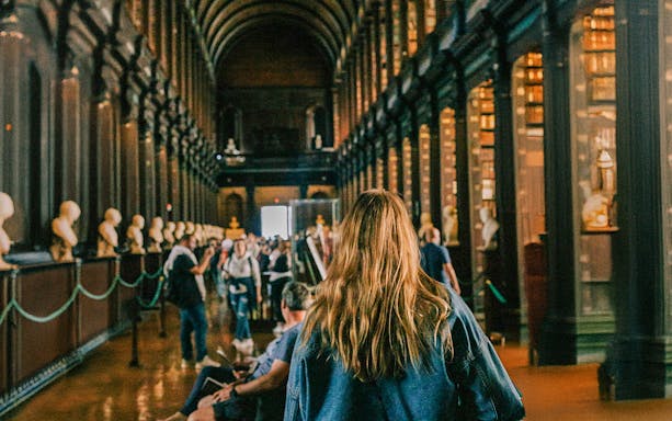 Visitors exploring the Long Room at Trinity College Library, Dublin.