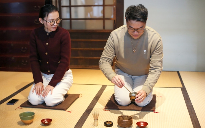 Guide demonstrating traditional tea-making process in a Japanese tea room.