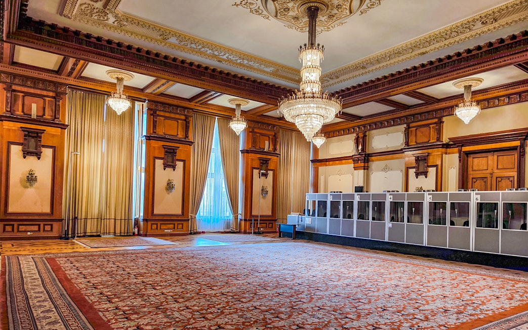 Palace of Parliament interior with ornate chandeliers and detailed wood paneling.