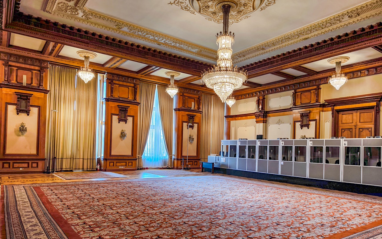 Palace of Parliament interior with ornate chandeliers and detailed wood paneling.