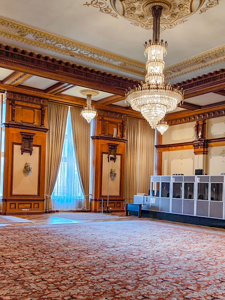 Palace of Parliament interior with ornate chandeliers and detailed wood paneling.