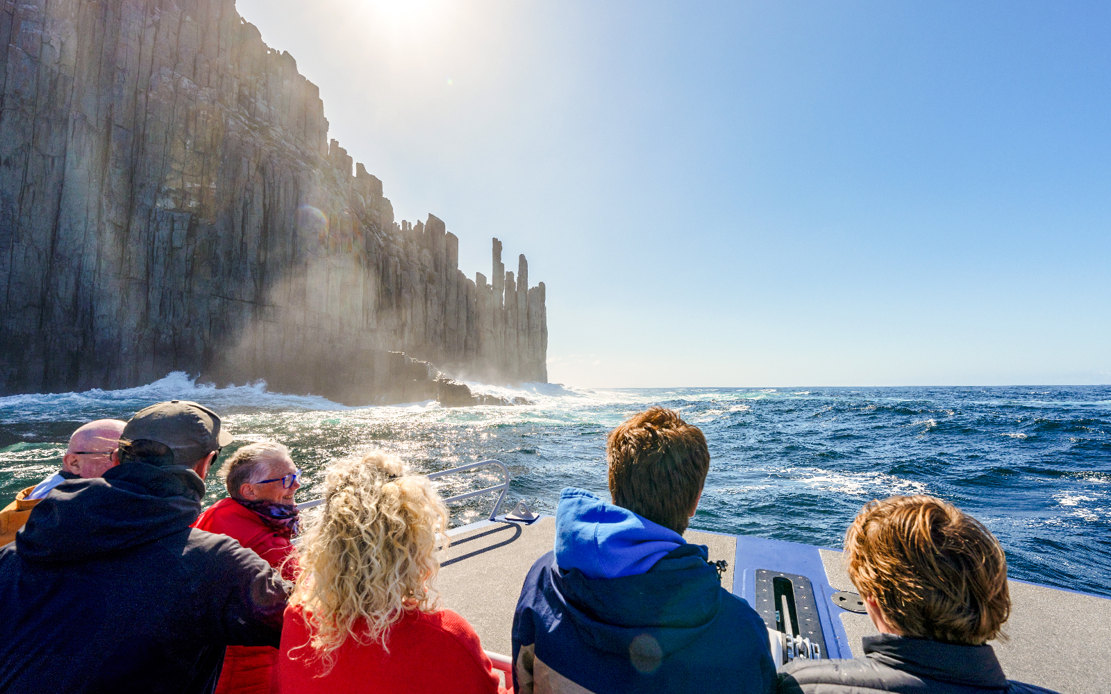 People on a boat viewing Cape Raoul cliffs during a cruise.