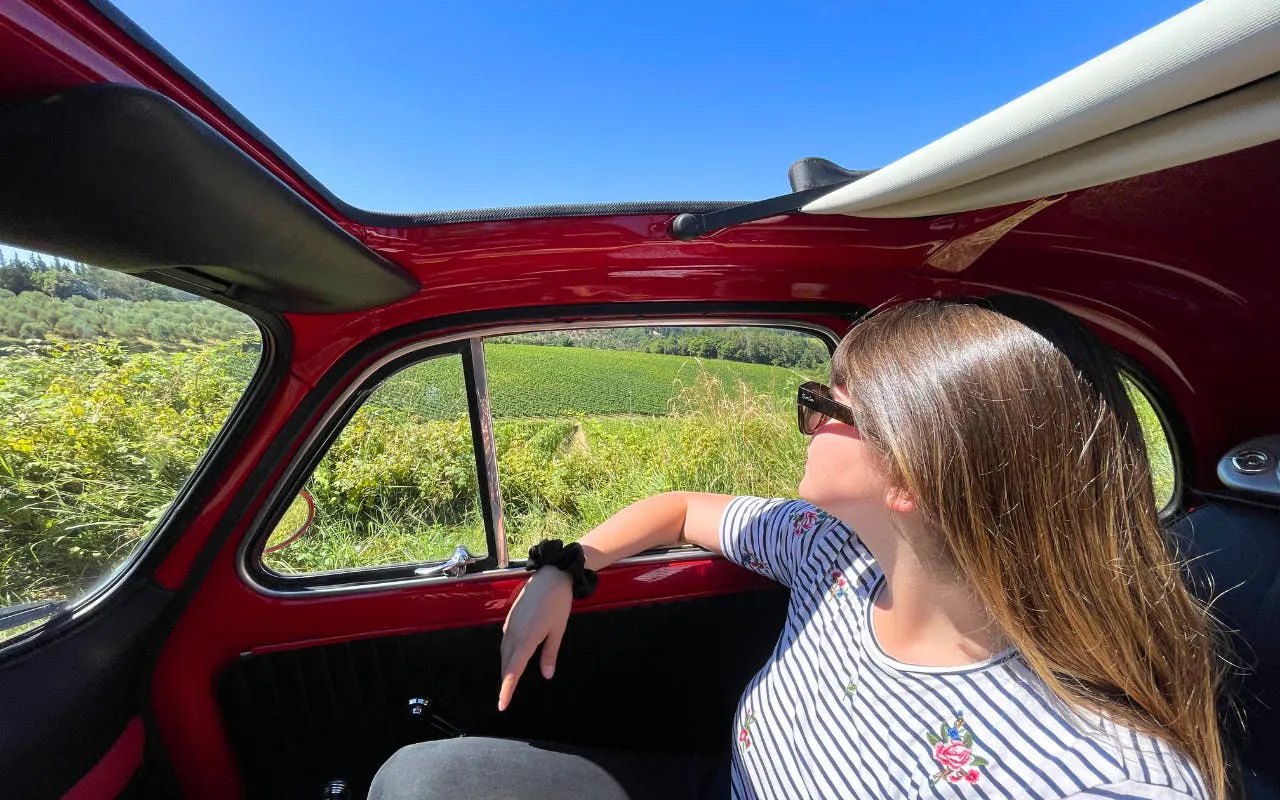 Vintage Fiat 500 drive through Chianti countryside with vineyard view.