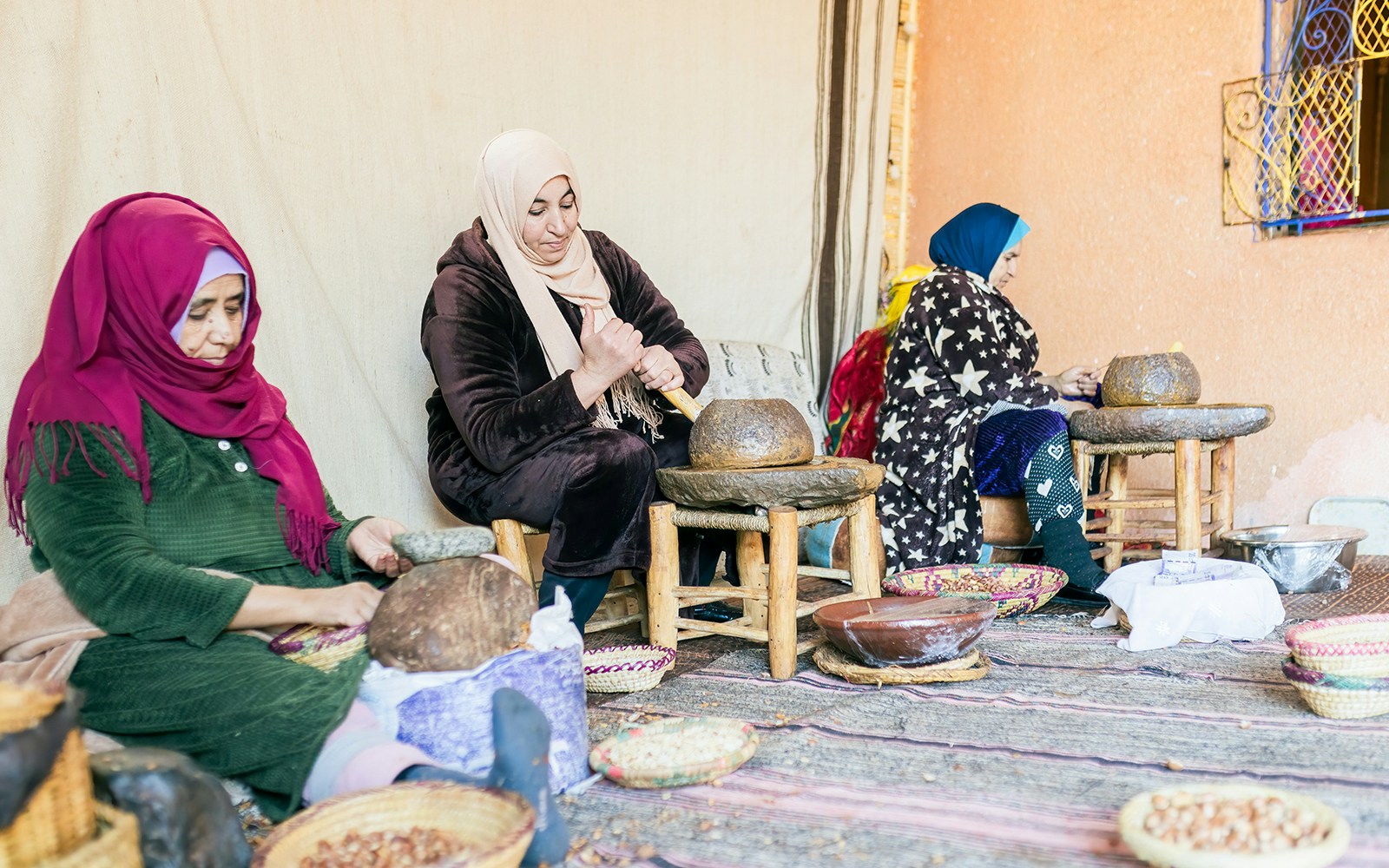 Women grinding argan nuts to extract oil in a traditional setting.