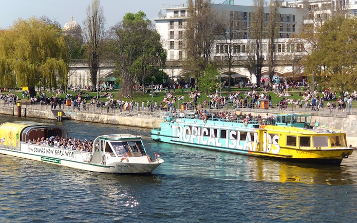 Sightseeing boats with passengers cruising on the Spree River in Berlin Mitte.