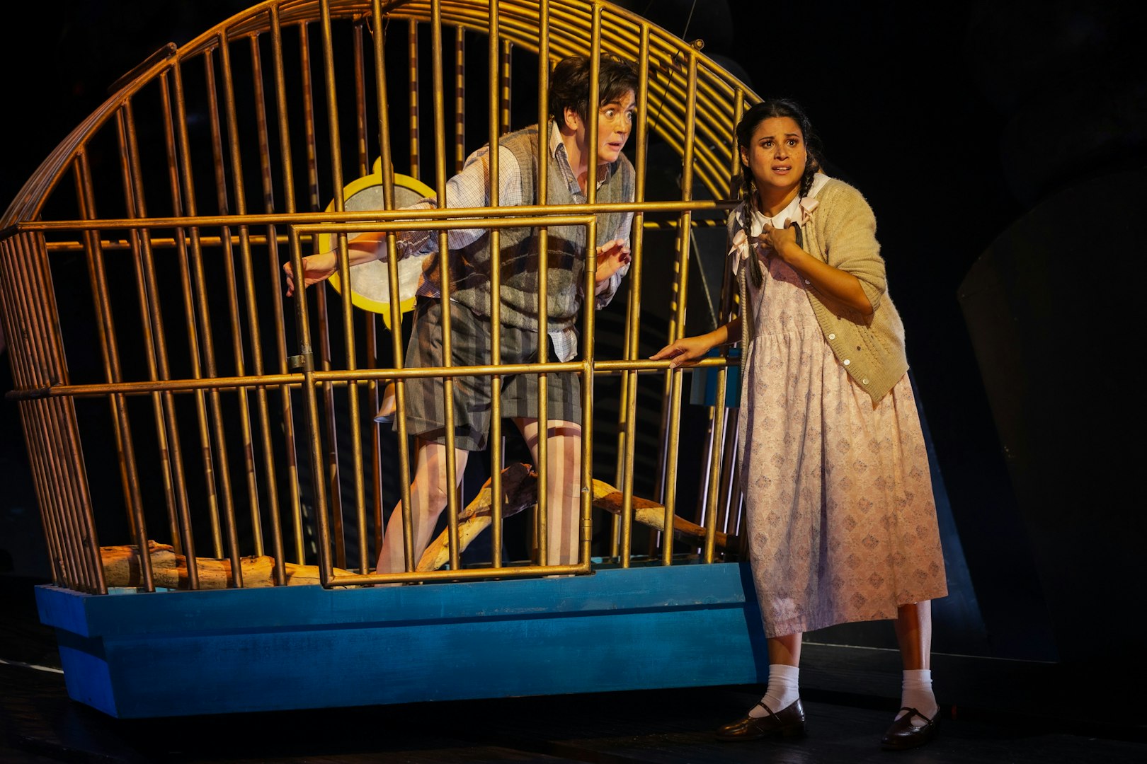 Hansel and Gretel stage performance with characters near a large cage.