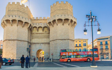 Valencia tour bus near Torres de Serranos with historic architecture.
