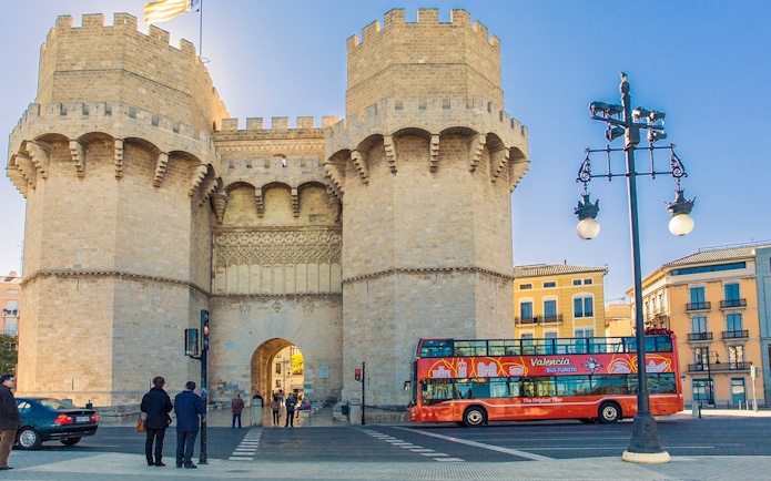 Valencia tour bus near Torres de Serranos with historic architecture.