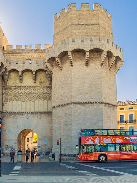 Valencia tour bus near Torres de Serranos with historic architecture.