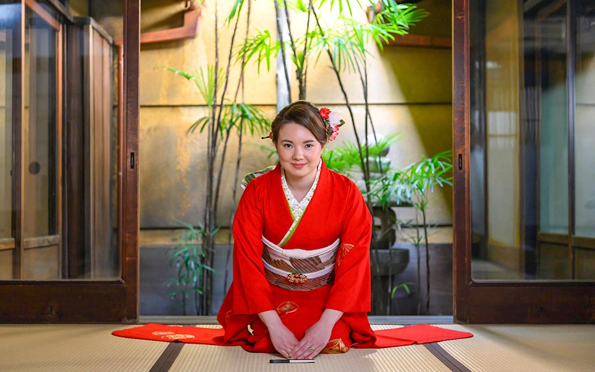 Kimono-clad woman in traditional Kyoto machiya during tea ceremony.