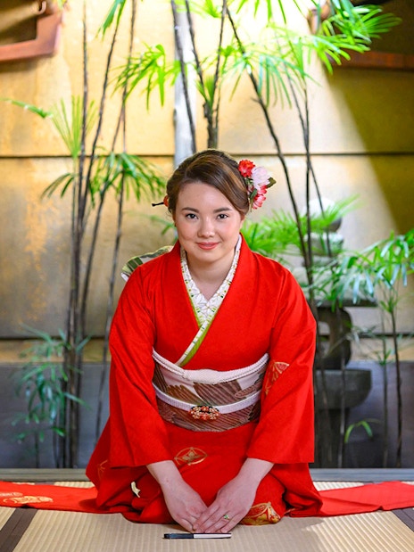 Kimono-clad woman in traditional Kyoto machiya during tea ceremony.