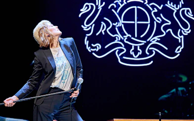 Performer on stage during Inter Alia show on Broadway with neon backdrop.