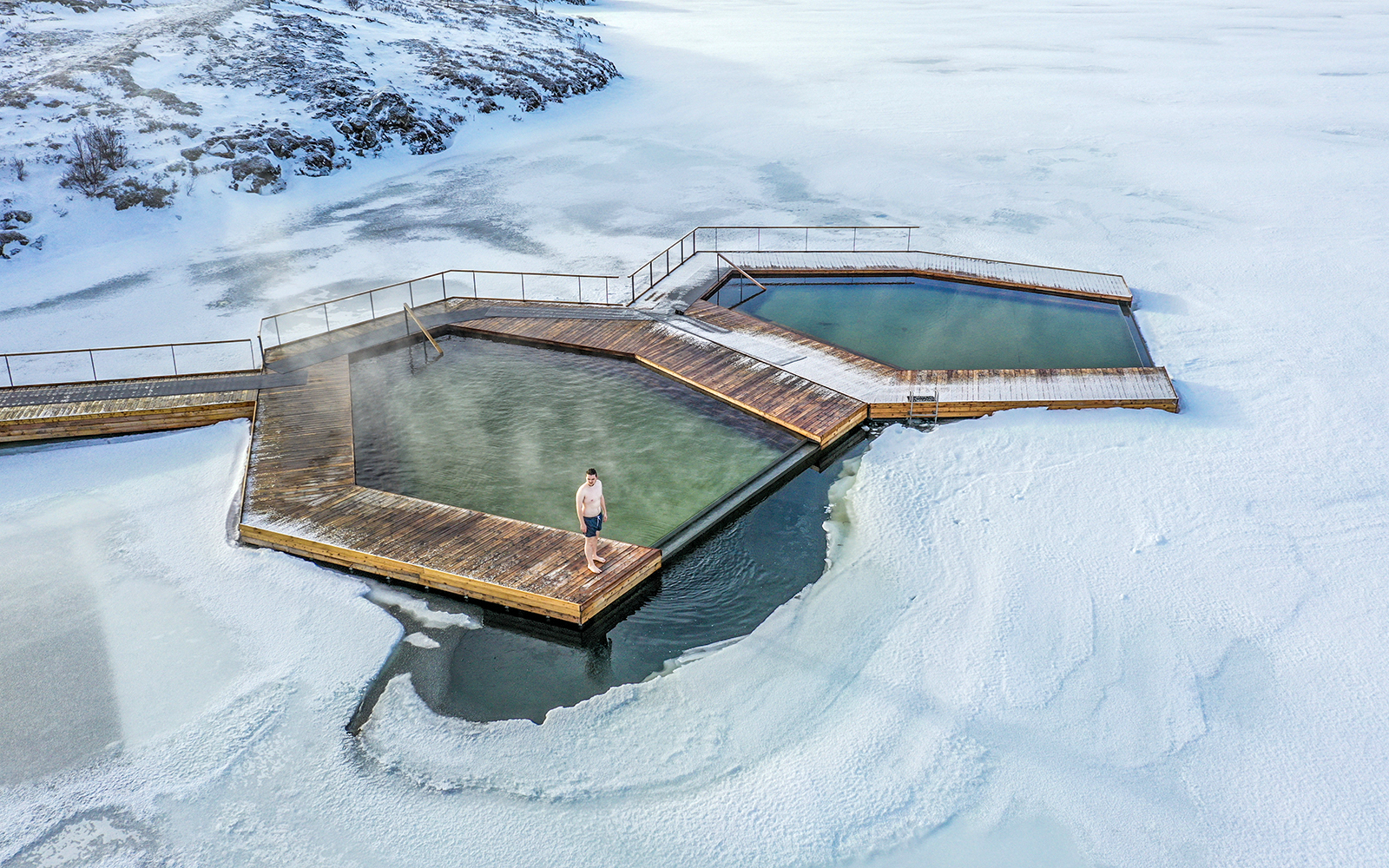Guests enjoying geothermal pools at Vök Baths, Iceland, surrounded by snow.