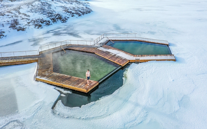 Guests enjoying geothermal pools at Vök Baths, Iceland, surrounded by snow.