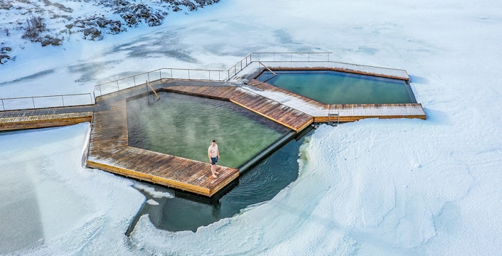 Guests enjoying geothermal pools at Vök Baths, Iceland, surrounded by snow.